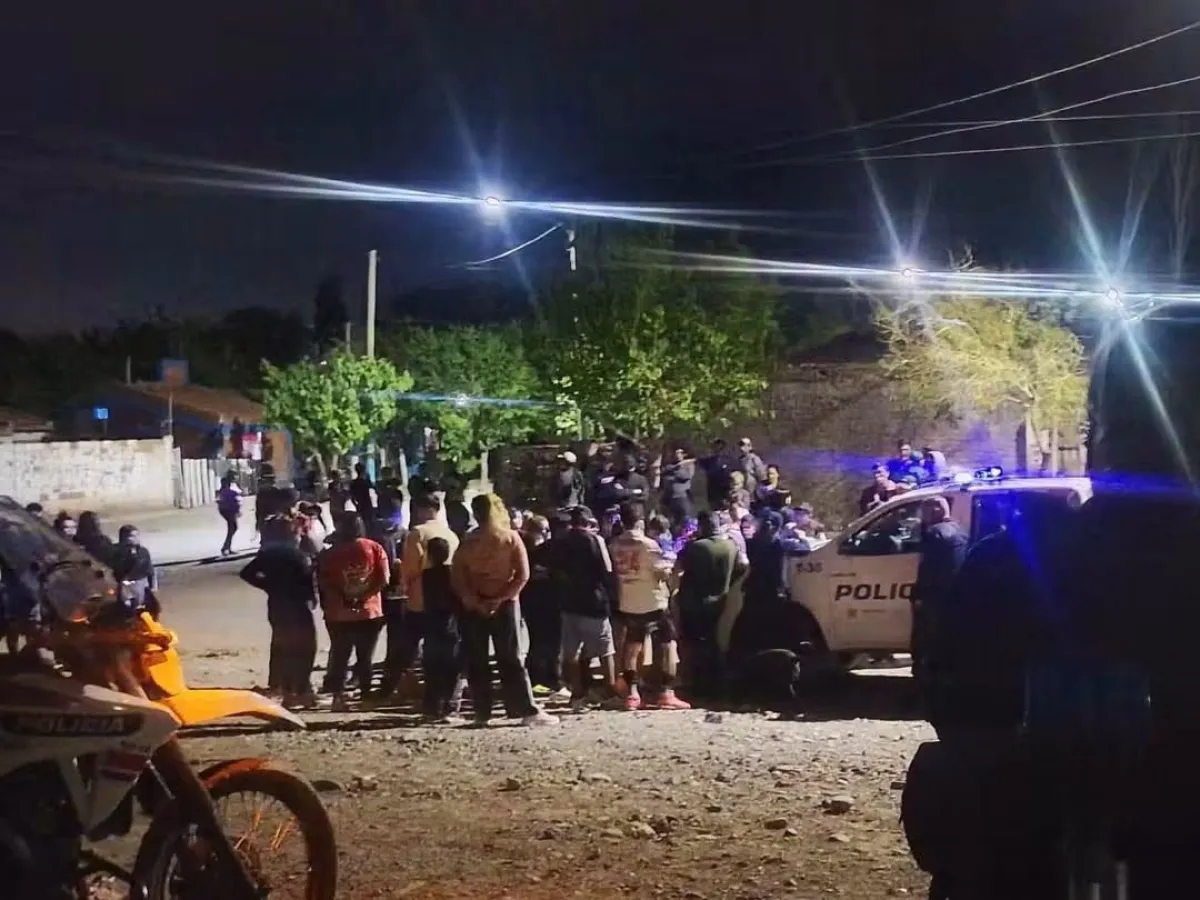Personas reunidas durante la noche junto a un móvil policial en Campo Afuera.