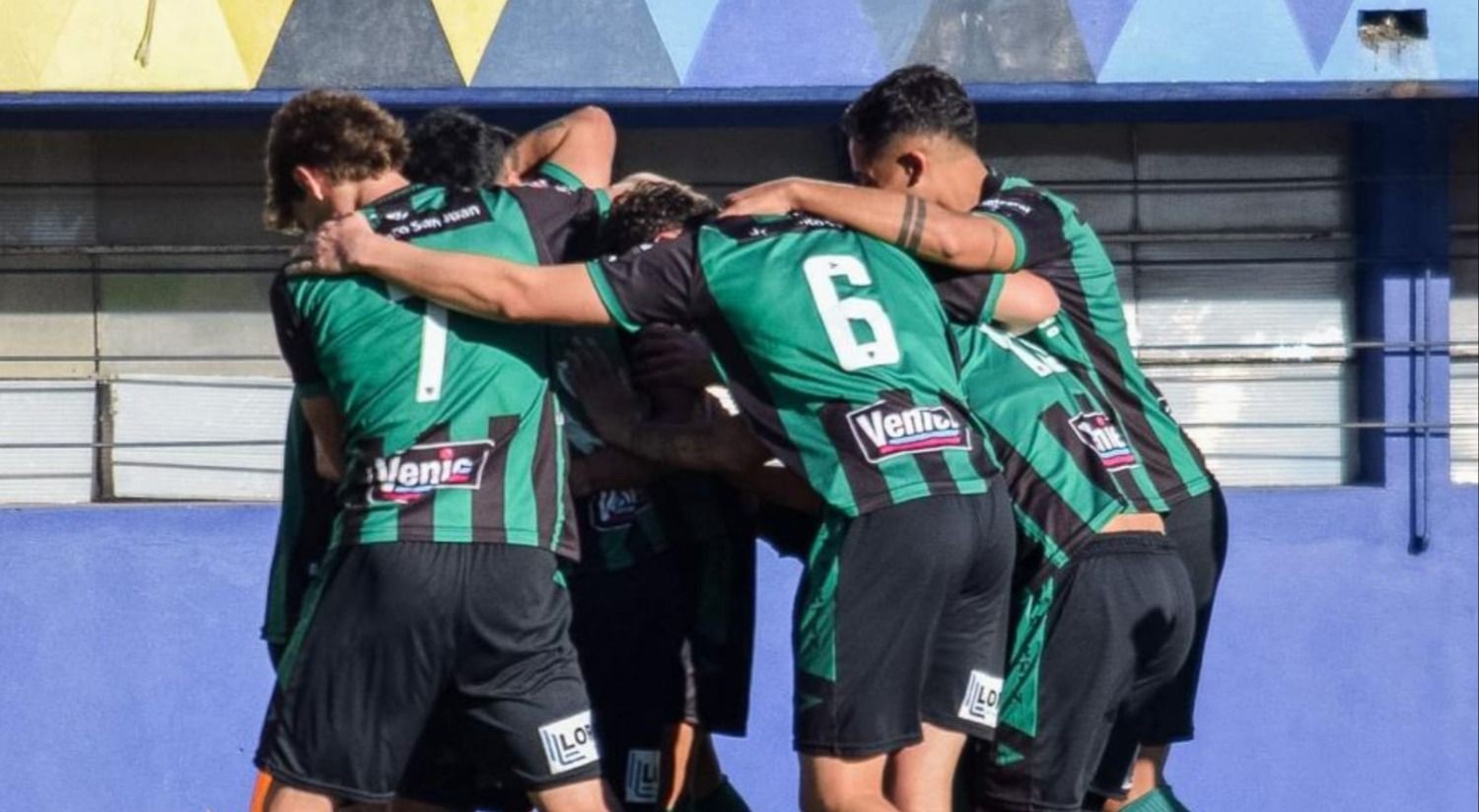Jugadores de San Martín con camisetas verdes y negras abrazados durante un festejo