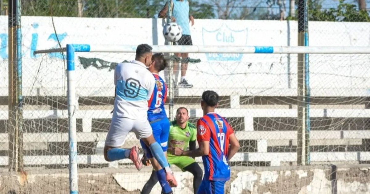 Jugadores disputan una pelota frente al arco en un partido de fútbol local