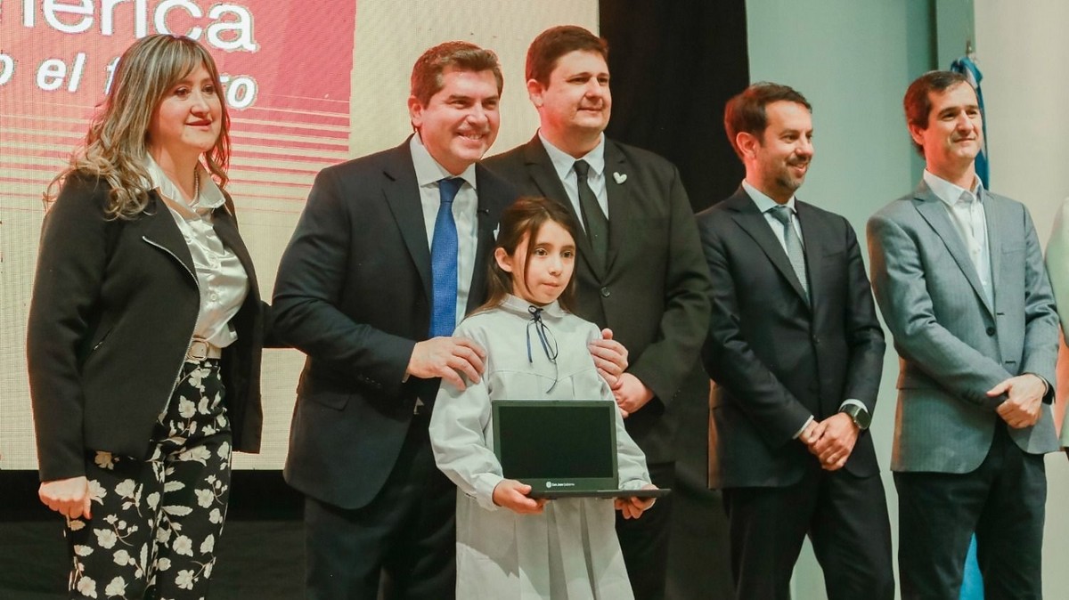 Una estudiante recibe una computadora junto a autoridades provinciales durante el acto.