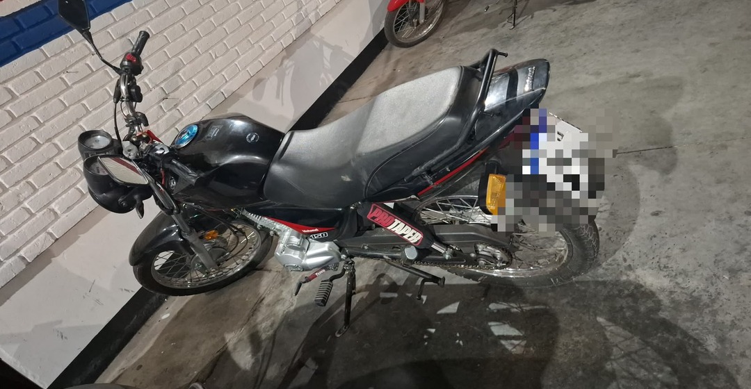 Moto negra sobre un piso de cemento, con la patente pixelada, en una imagen del procedimiento en Pocito.