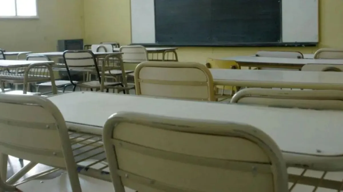 Pupitres y pizarrón en un aula vacía.