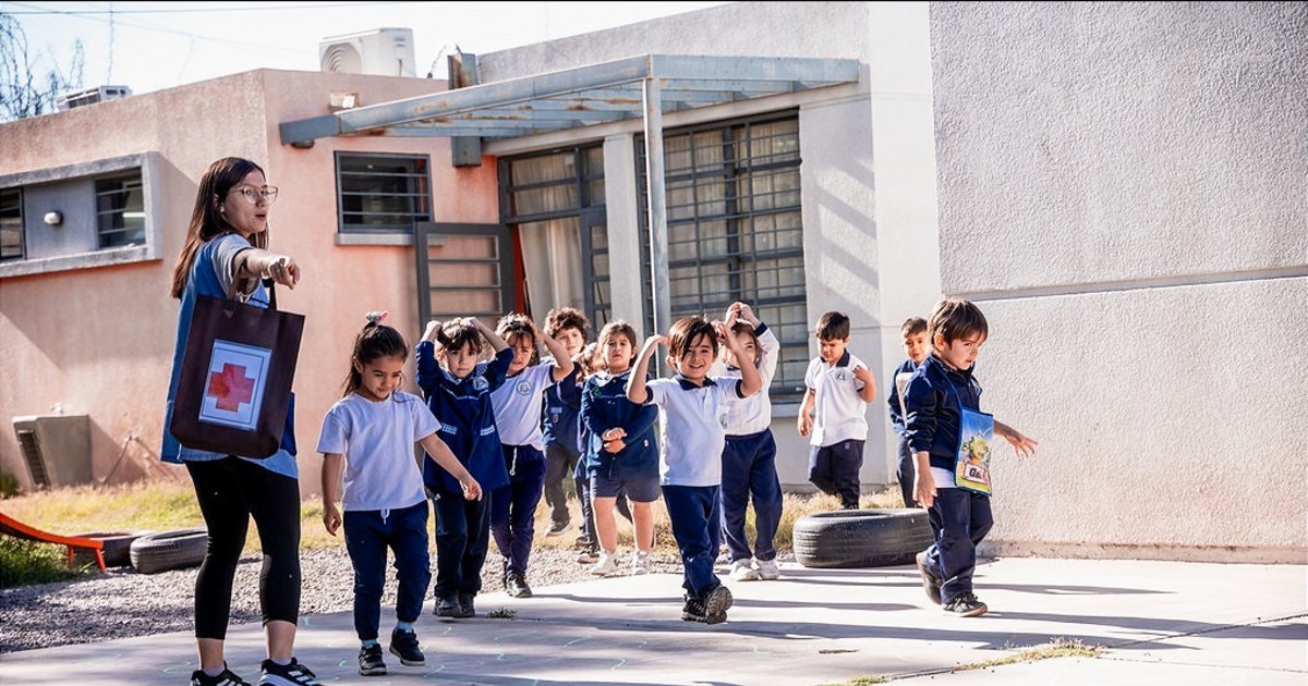 Una docente guía a niños durante un ejercicio de evacuación escolar.