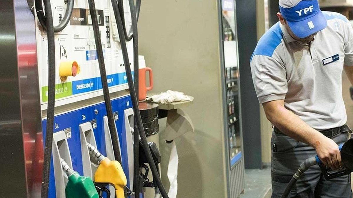 Empleado de una estación YPF carga combustible junto a los surtidores.