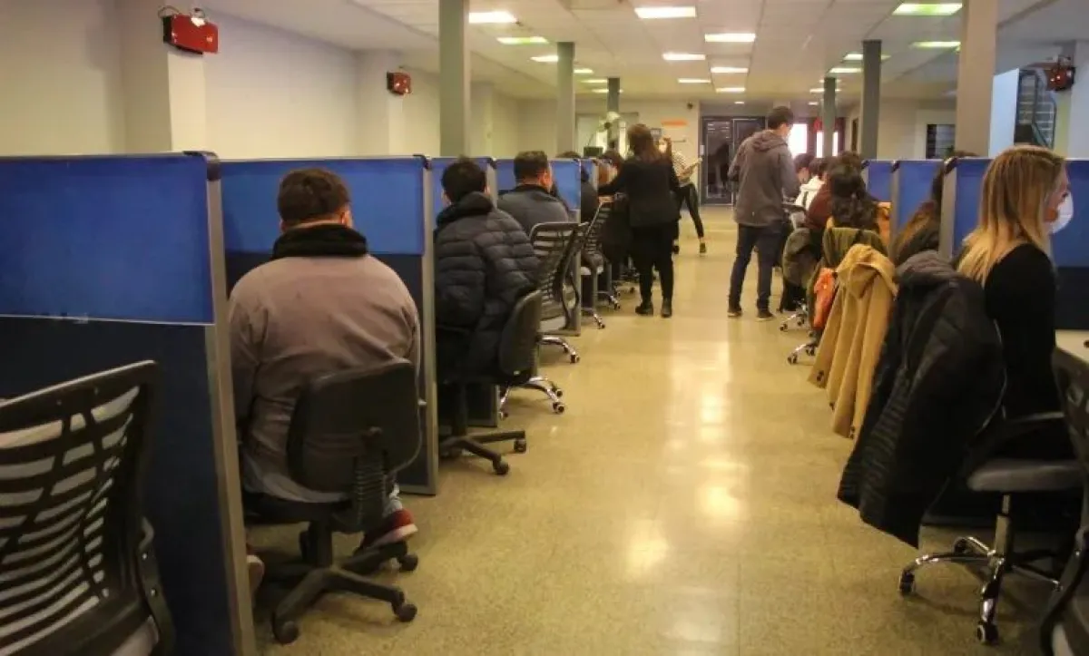 Personas sentadas frente a computadoras en una sala de evaluación.