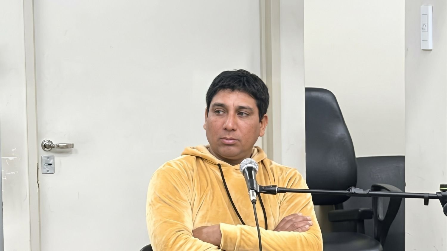 Facundo Nievas, sentado con los brazos cruzados frente a un micrófono durante una audiencia