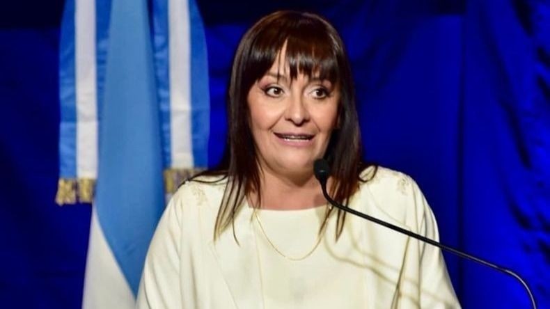 Daniela Rodríguez, intendenta de Chimbas, habla ante un micrófono con la bandera argentina de fondo