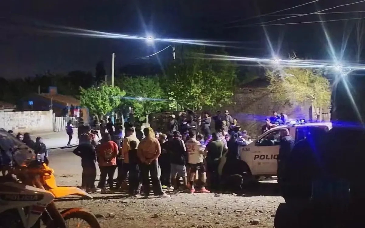 Personas reunidas durante la noche junto a un móvil policial en Campo Afuera.