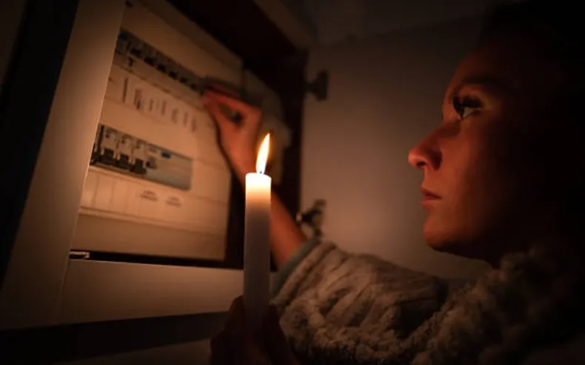 Fotografía de referencia de una mujer frente a un tablero eléctrico, iluminada por una vela.