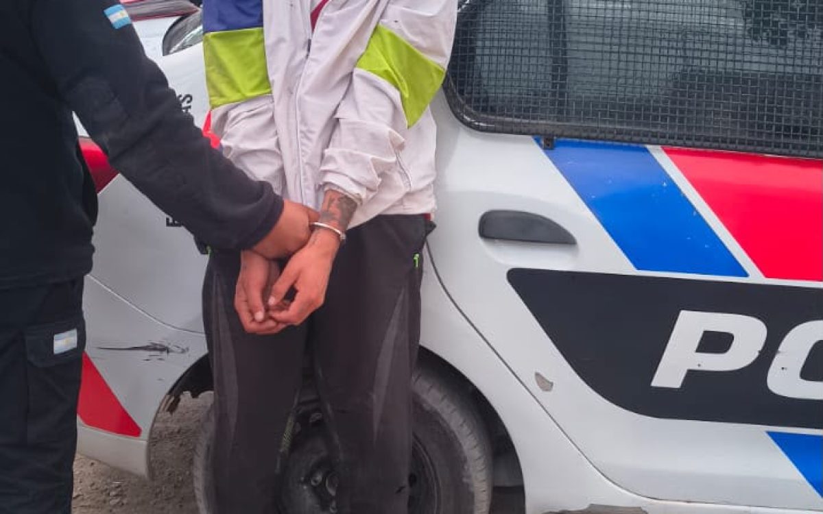 Hombre con rostro pixelado junto a un móvil policial, en la fotografía aportada sobre la aprehensión en el Lote Api II, Chimbas