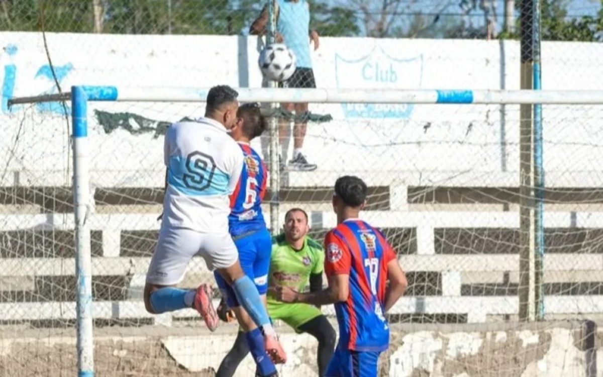 Jugadores disputan una pelota frente al arco en un partido de fútbol local