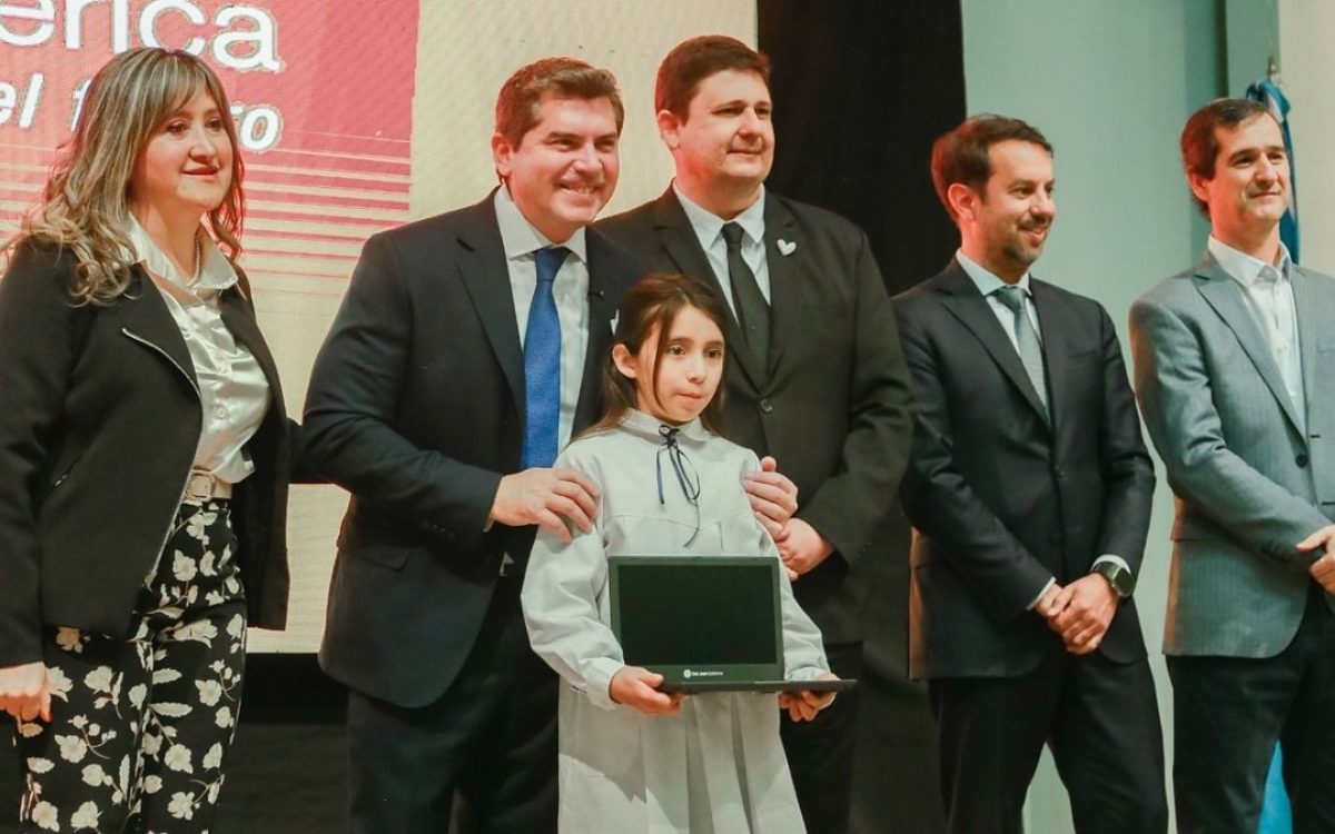 Una estudiante recibe una computadora junto a autoridades provinciales durante el acto.