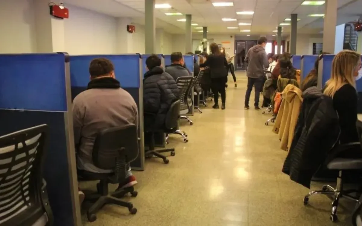 Personas sentadas frente a computadoras en una sala de evaluación.