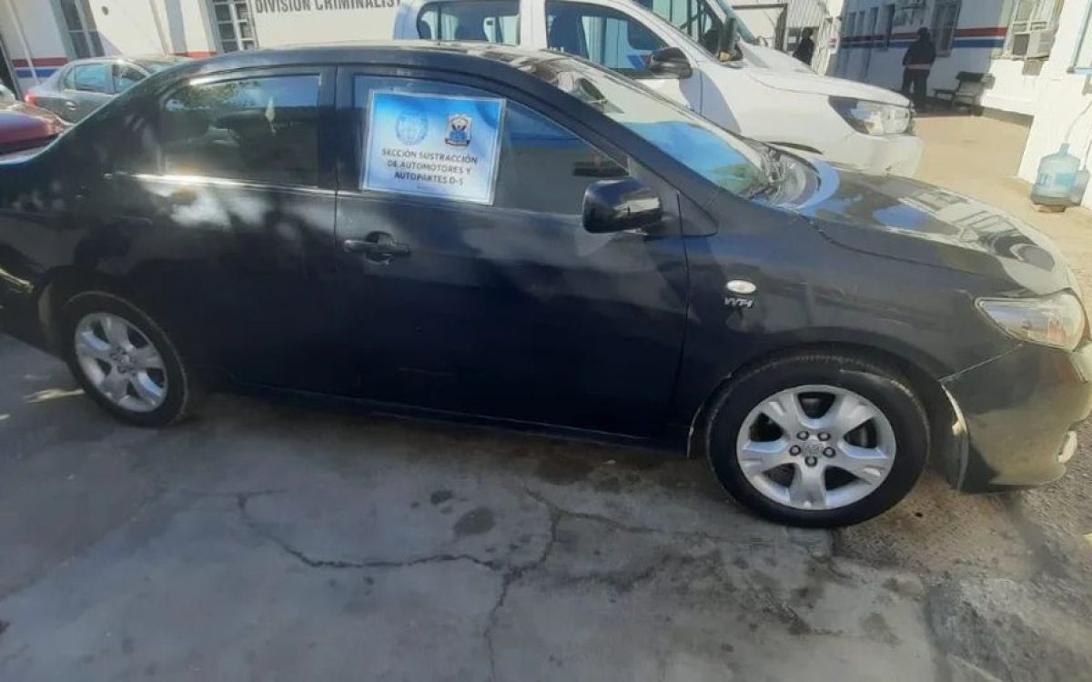 Toyota Corolla gris oscuro en un predio policial, con un cartel de Sustracción de Automotores en el vidrio.