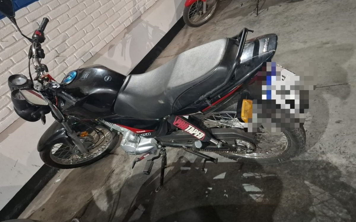 Moto negra sobre un piso de cemento, con la patente pixelada, en una imagen del procedimiento en Pocito.