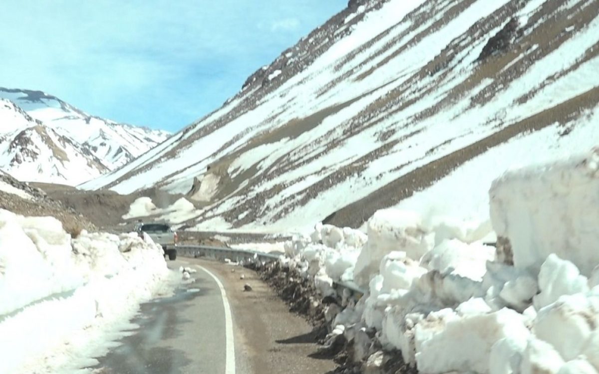 Camino cordillerano con nieve acumulada a ambos lados de la calzada.