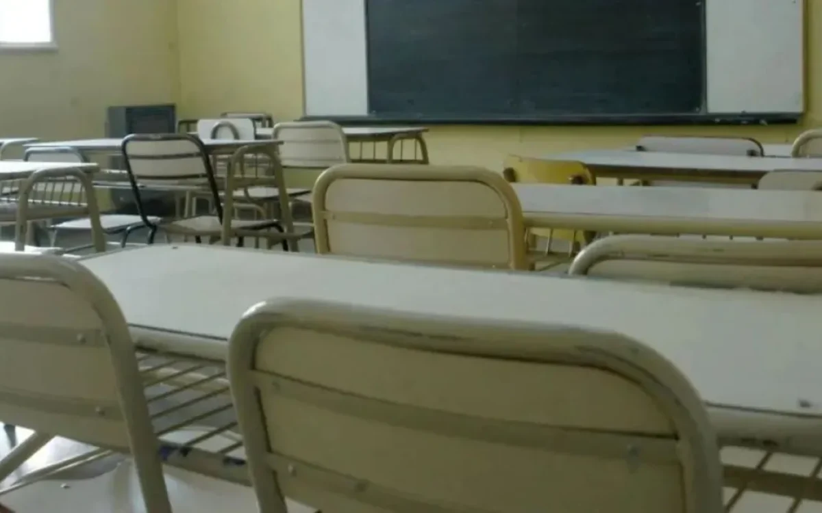 Pupitres y pizarrón en un aula vacía.