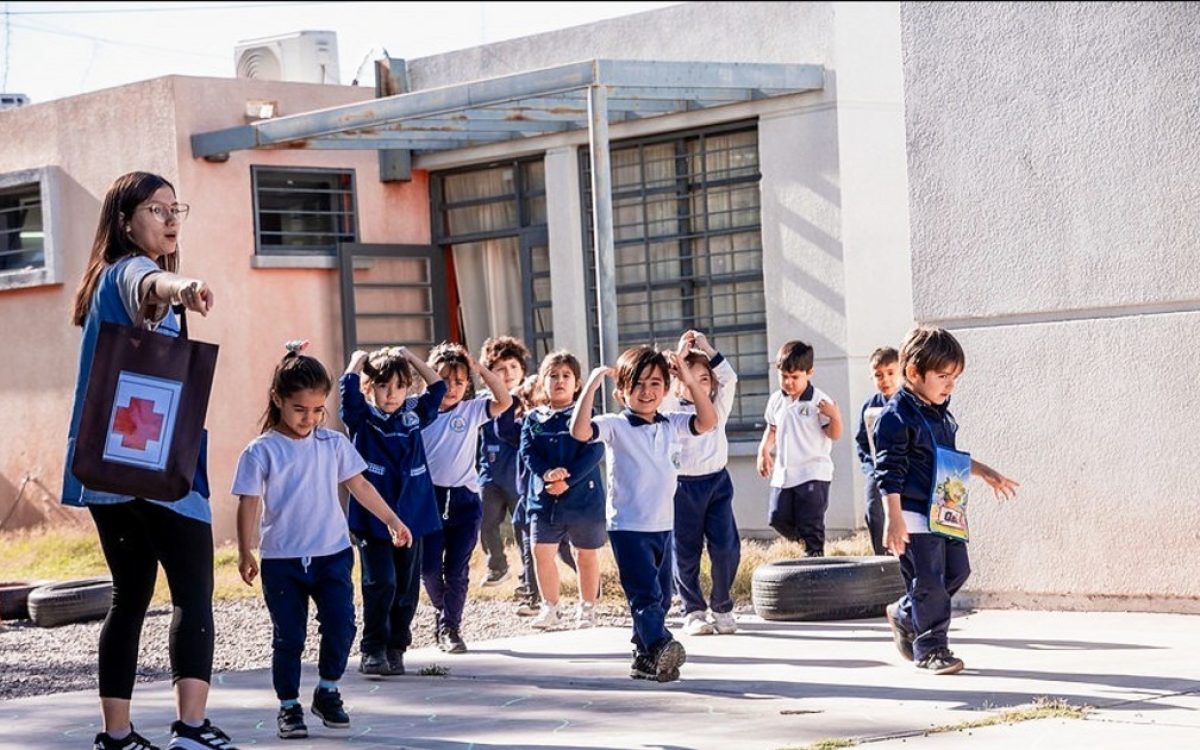 Una docente guía a niños durante un ejercicio de evacuación escolar.