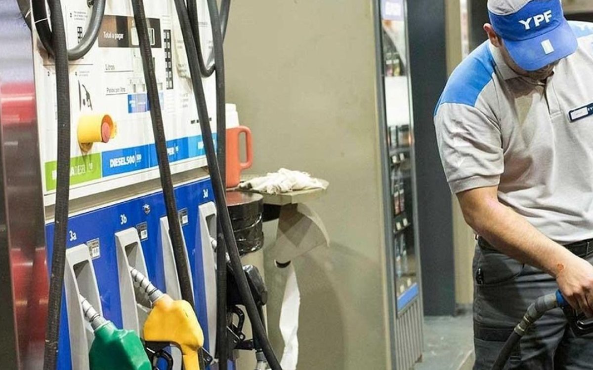Empleado de una estación YPF carga combustible junto a los surtidores.